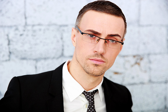 Handsome businessman standing near brick wall