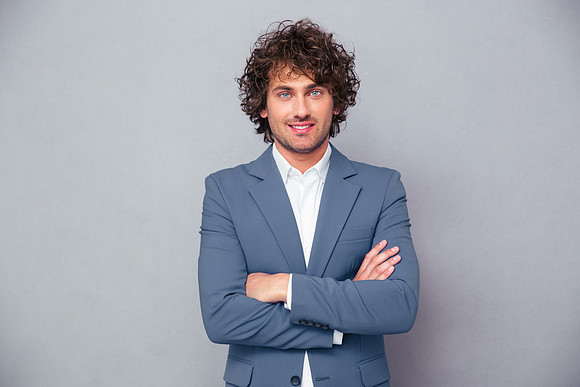 Cheerful businessman standing with arms folded